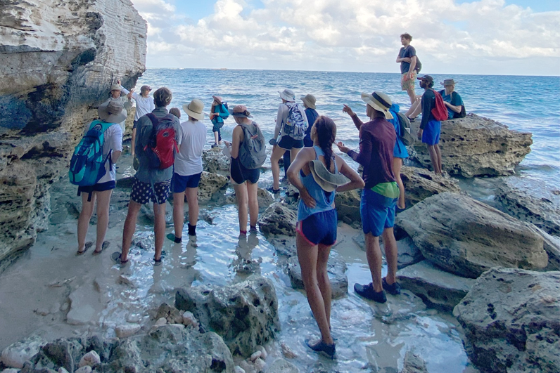 Students in front of a mural that reads "We are what we are doing to change who we are."