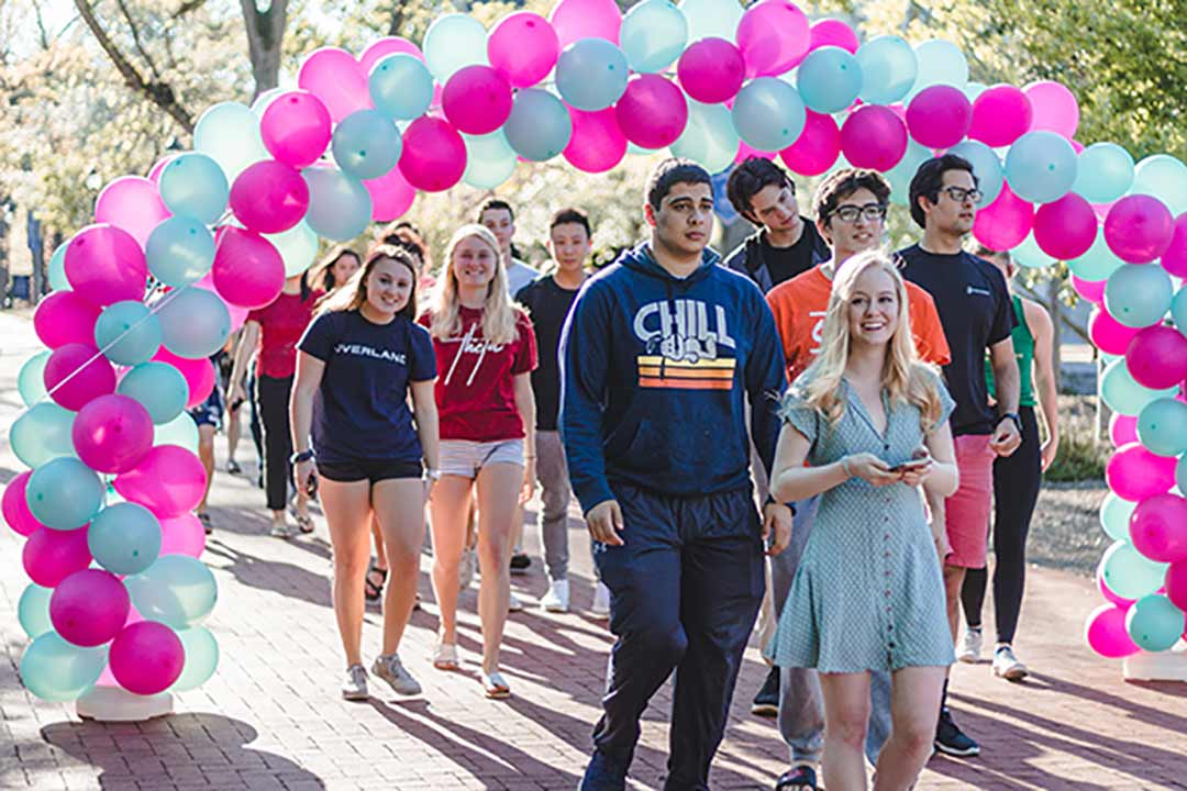 Students walk through a balloon arch.