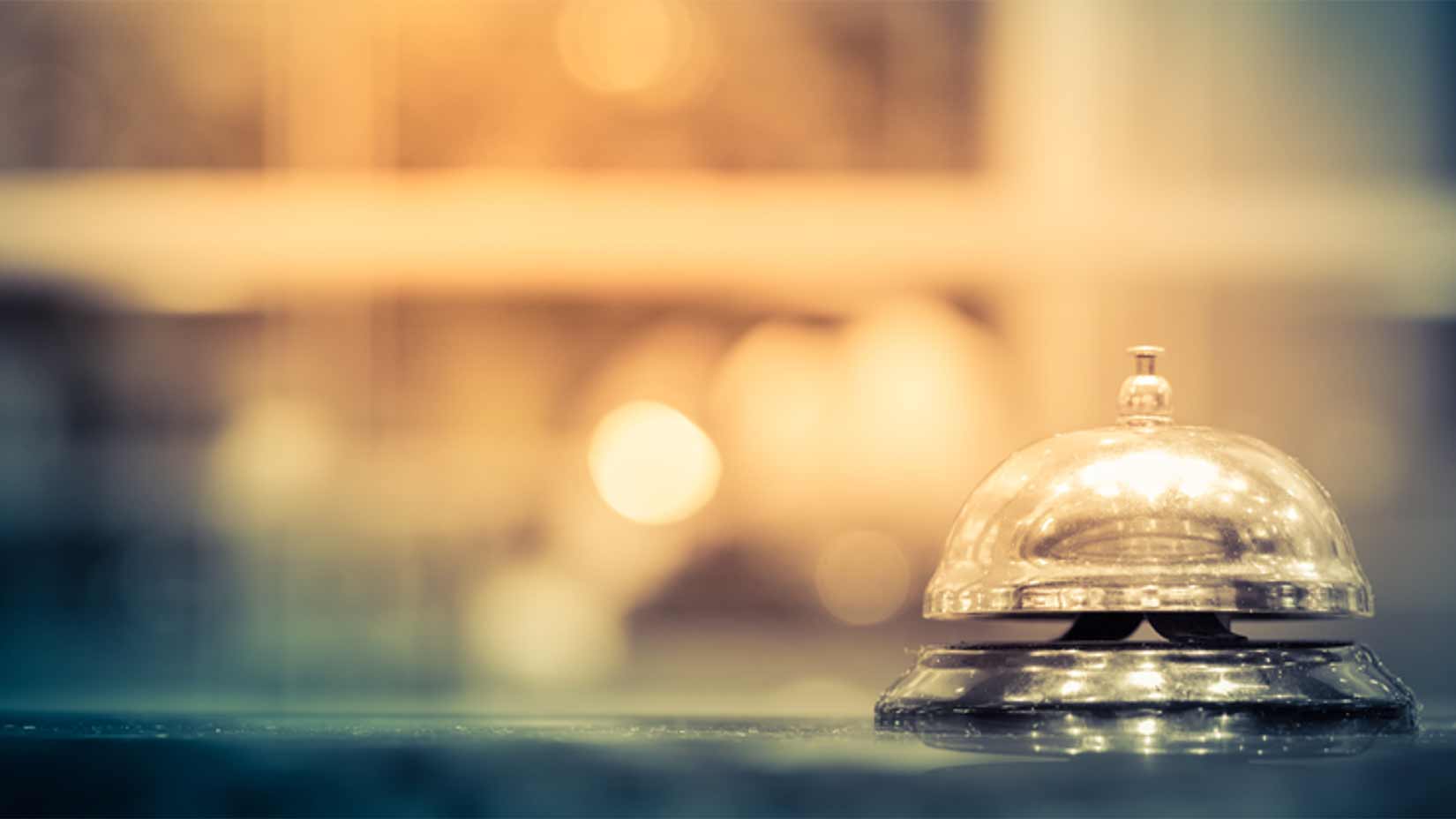 A bell sits on a hotel reception desk.